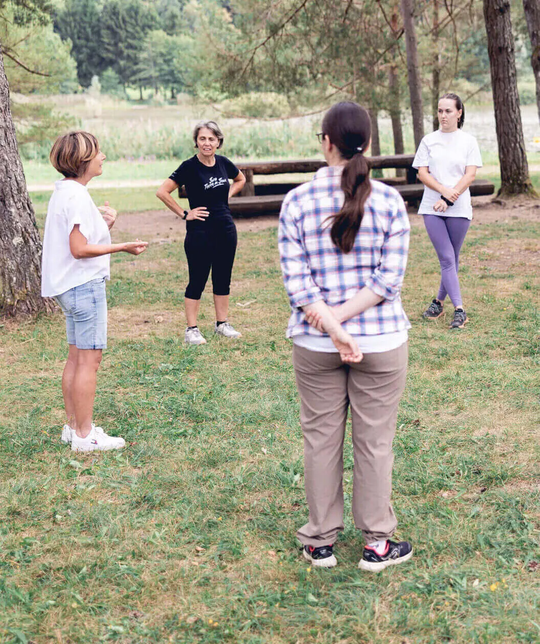 La formatrice Ilse Geusens partage des outils et techniques à un groupe de participants qui se tient en cercle devant elle et qui l’écoute avec attention.