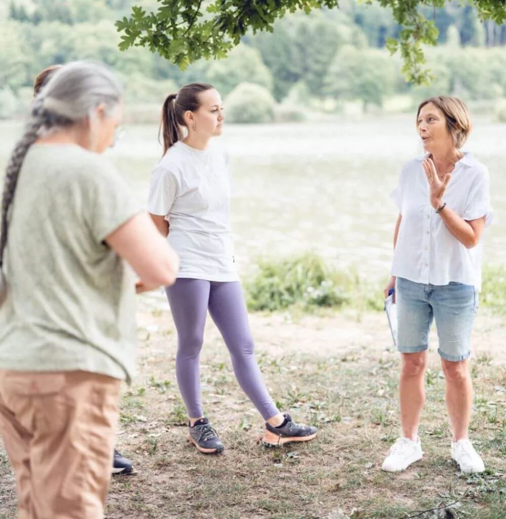 Tout près d’un lac du Jura, Ilse Geusens explique comment affiner son intuition à un groupe de participants qui se tient debout et qui l’écoute très attentivement.