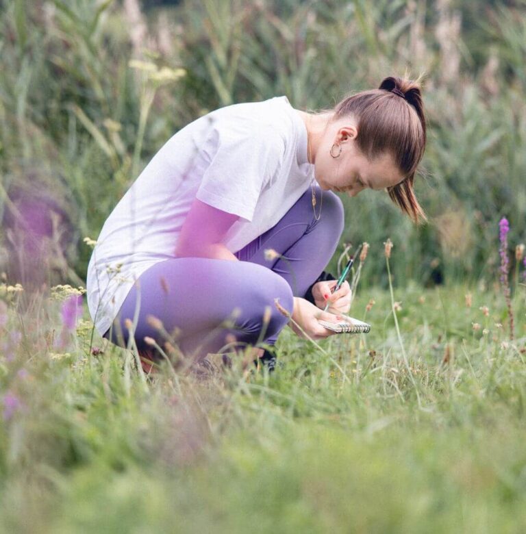 Une infirmière se tient accroupie dans un champ de lavande jurassien et est en train d’écrire sur son calepin ce qu’elle observe et ressent au plus profond d’elle.