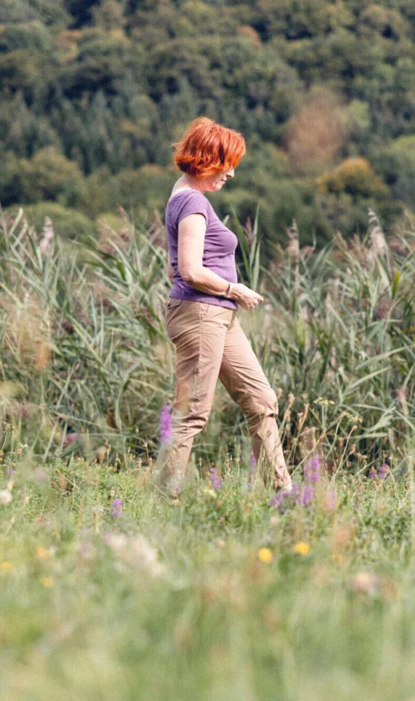 Une patiente se promène seule dans un champ fleuri, se sentant en paix et profondément nourrie par la nature.