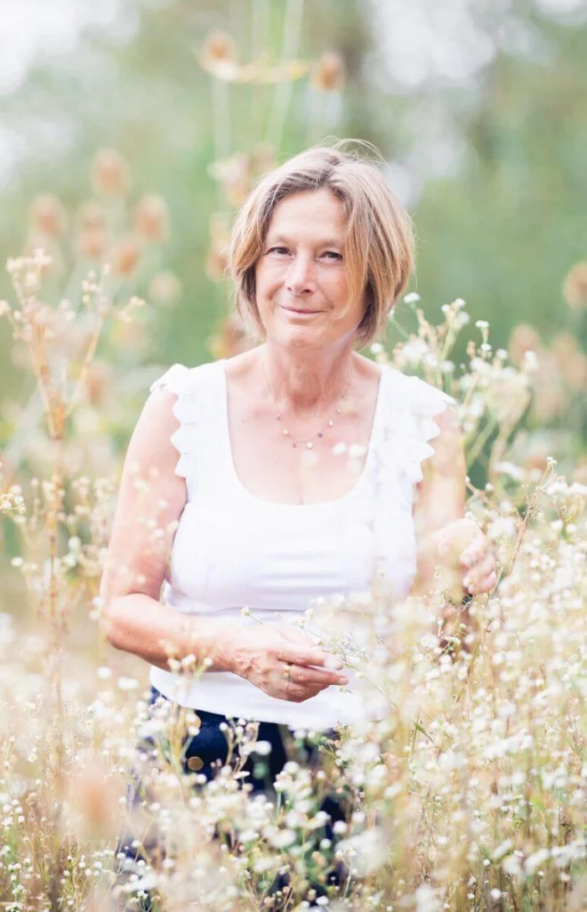 Au milieu d’un champ avec de grandes fleurs blanches, portrait professionnel d’Ilse Geusens, formatrice en écothérapie.